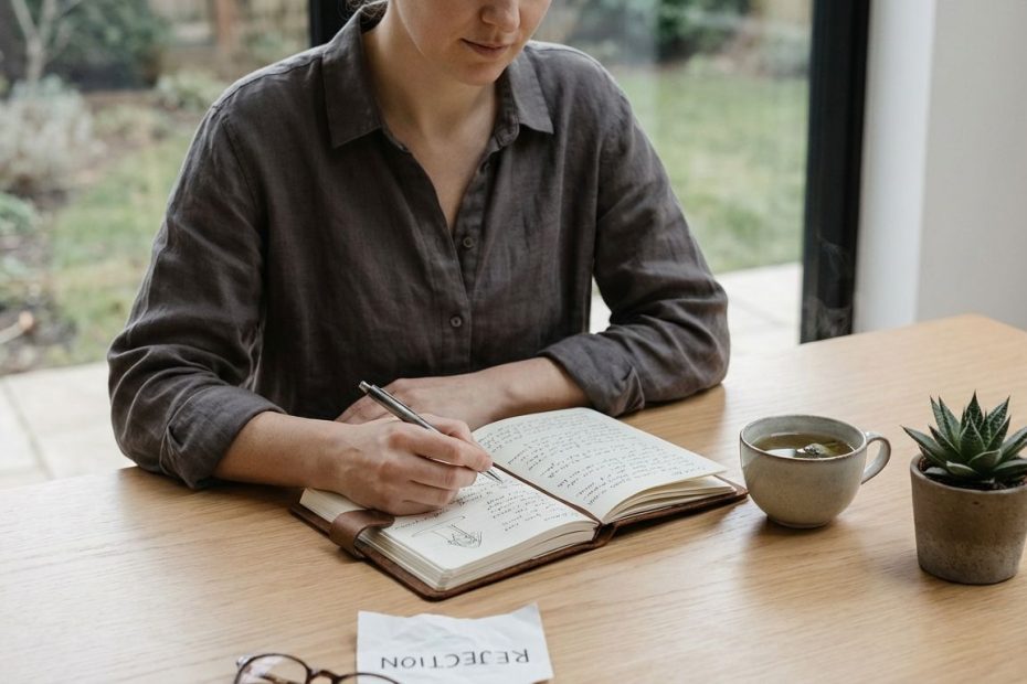 Person journaling after rejection with calming breath and a clear next-step plan