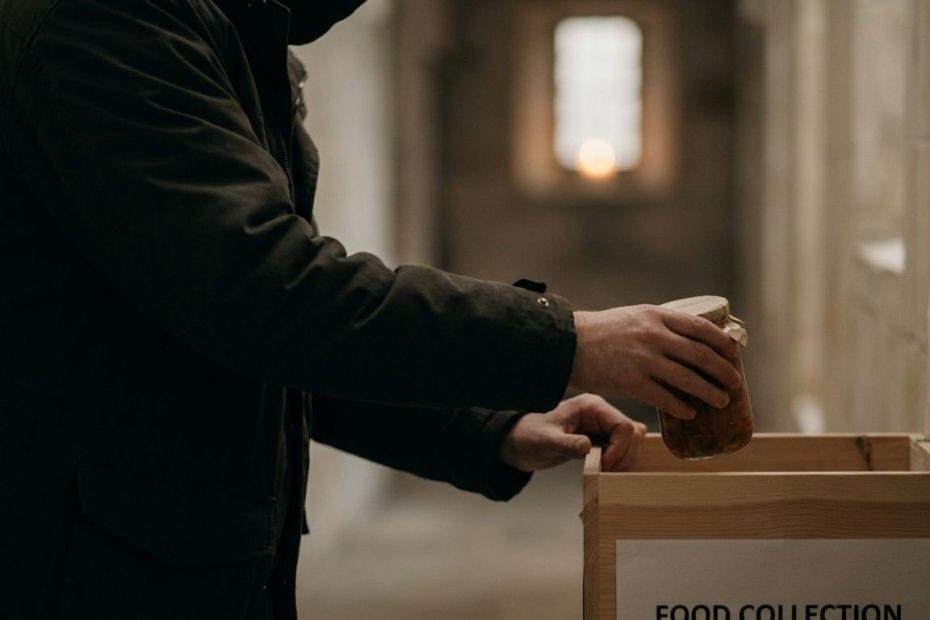 Person placing a grocery bag into a community donation box to help strangers